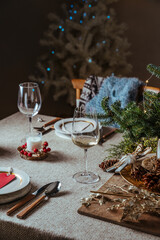 Naklejka na ściany i meble Homely christmas table setting, decorated with pine branches and rustic tablecloth in the living room of home tree lit background