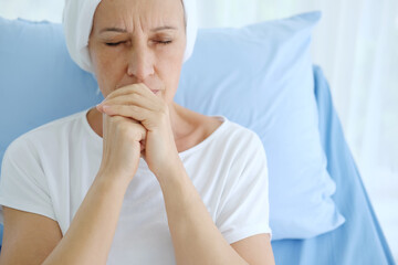 Caucasian Elderly Mother in white headscarf is laying on bed in hospital after chemotherapy because...