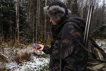Hunter with smartphone in a winter forest