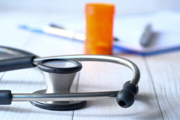 stethoscope and pills container on wooden background 