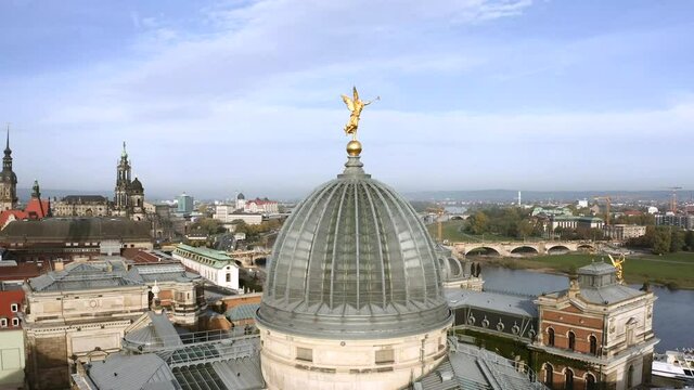 Drone footage of golden Fama figure statue on top of Zitronenpresse with Frauenkirche in background in Dresden, Germany