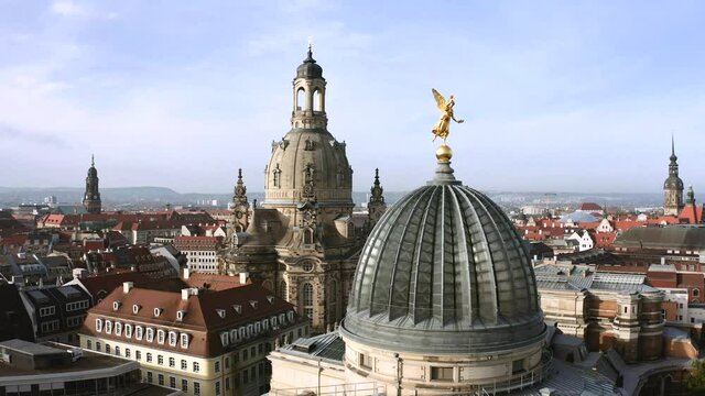 Drone footage of golden Fama figure statue on top of Zitronenpresse with Frauenkirche in background in Dresden, Germany