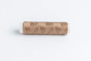 One vivid brown cotton spool of thread isolated on a white table.