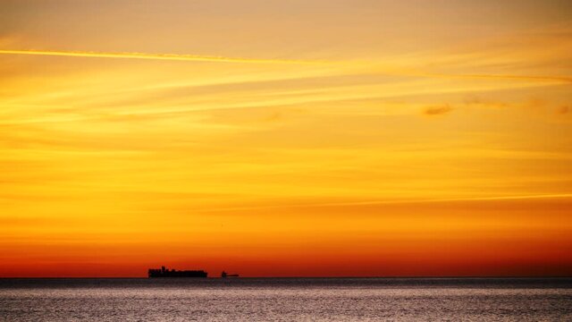 Seascape at sunrise with cargo container industrial ships stand in the roadstead on Gibraltar Strait, view from spanish coast. Logistic shipping concept.