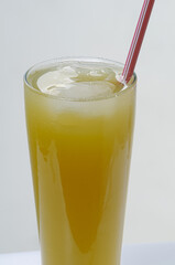 Brazilian gastronomy. Glass cup with cane juice and plastic straw, on white background. Traditional cheap drink, widely consumed throughout Brazil.