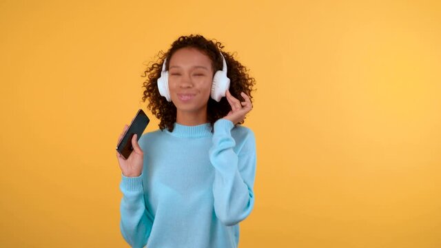 funny cute mixed race woman she listens to music in the earpiece and sings with her phone.