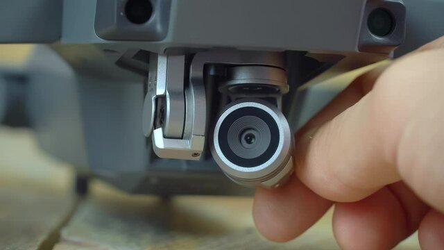 Extreme close-up shot of a modern drone camera mounted on a gimbal. The man turns it with his finger in all directions.