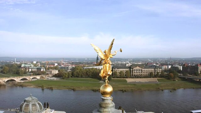 Drone footage of golden Fama figure statue on top of Zitronenpresse with Frauenkirche in background in Dresden, Germany