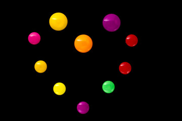The shape of the heart is made of colored plastic magnets on a black background (top view).