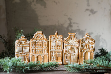 Christmas cookies gingerbread houses on wooden table with grey wall in background, selective focus.