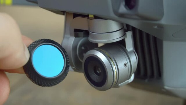 A close-up shot of a hand holding an nd or pl neutral density filter for unmanned cameras, drones, or copters.