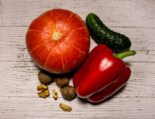 Pumpkin, peppers, cucumber and nuts on a light wooden background