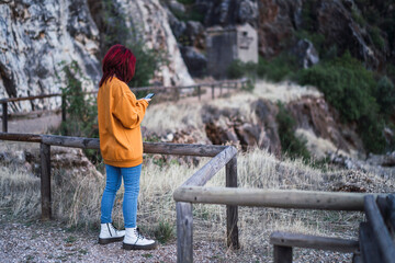 Chica peliroja en parque natural tomando fotogarfías 