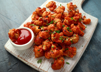 Vegan cauliflower buffalo wings on white wooden board