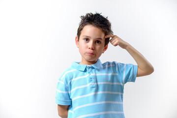 Fototapeta premium A boy in a blue T-shirt looks at the camera with a playful and thoughtful look.