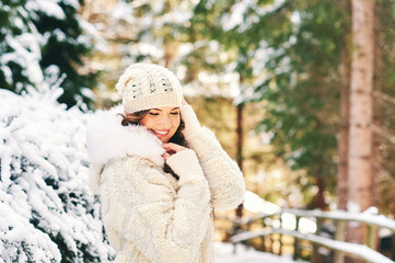 Seasonal winter portrait of middle age woman enjoying nice sunny day in forest, wearing white cozy...