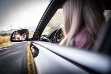 Young woman driving car with protective mask on her face.