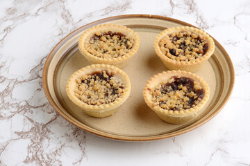 four fruit crumble tarts on a brown plate