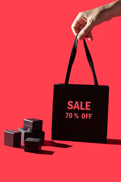 hand holding  shopping bag and black bpxes on red background for sale and shopping  concept. Copy space