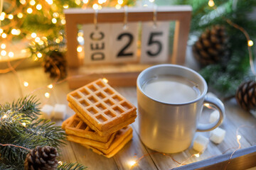 Coffee with milk and Belgian waffles on a wooden tray against a background of garlands and spruce...
