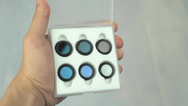 Close up shot of a hand holding a set of neutral density filters for drone cameras