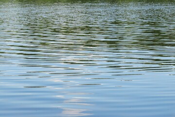 Ripples on light blue river water surface, reflection on the water