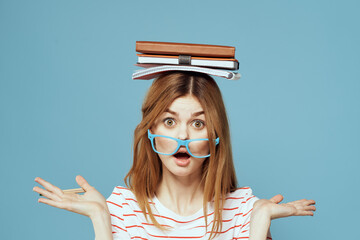 Female student with books on her head science education blue background emotions gesturing with...