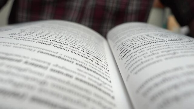 Close up panning video of an open book. Selective focus on example text book. Class notebook. Motion in the middle of a book with an example text.