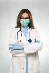 Female young doctor folded hands with protection medical mask, stethoscope over neck and white coat. Covid 19, coronavirus, healthcare concept banner.