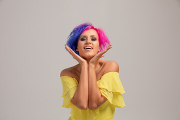 Portrait of a woman with bright colored hair, blue and pink haircut. girl with short hair dressed to yellow dress with open shoulders