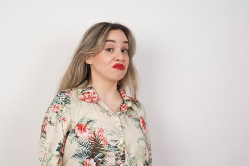 Beautiful woman standing against orange background, with snobbish expression curving lips and raising eyebrows, looking with doubtful and skeptical expression, suspect and doubt.