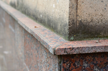 Outer corner of the building lined with light stone and red granite.