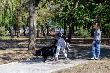 Happy children walk leisurely through the park with black Labrador.