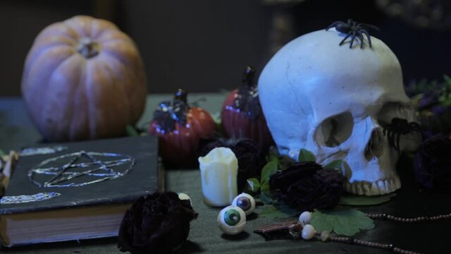 Bokeh of human skull and black book with pentagram, change of focus. The concept of a witch's table for rituals on the eve of halloween.
