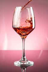 splash of red wine in glass on red background