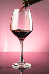splash of red wine in glass on red background