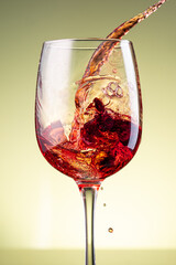 splash of red wine in glass on yellow background