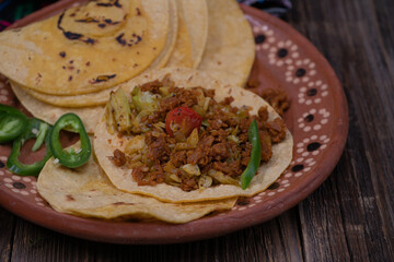 Vegan picadillo and tacos made with seitan, cabbage, spices, on wooden table in traditional serving bowls
