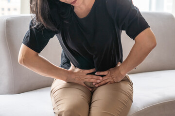 Abdominal pain in woman with stomachache illness from menstruation cramps, stomach cancer,...