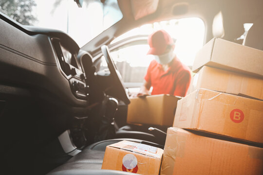 New normal express-Delivery services courier wearing medical mask for safety protection from virus infection working with postal boxes on delivery car