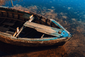 Close up of an old wooden decayed boat floating in shallows