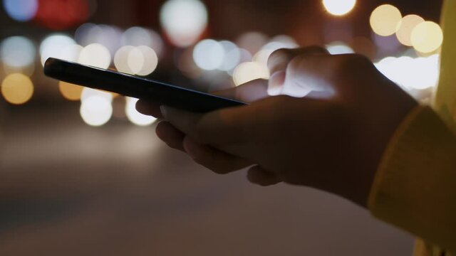  Hand of asian woman are communication chat on smartphone. On a blurred background and dark roadside night lights.	
