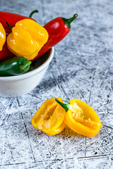 Sliced yellow habanero against a bowl full of colorful peppers