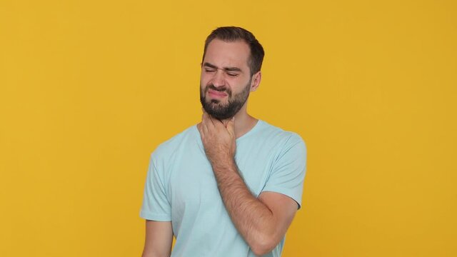 Young man in blue t-shirt put hand on neck throat isolated on yellow background studio. Healthy ill sick feel bad disease cold season Epidemic pandemic coronavirus 2019-ncov covid-19 flu virus concept