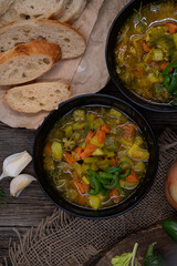 Celery, potato and carrot soup in black bowls in a rustic setting on wooden table