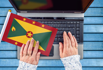 woman hands and flag of Grenada on computer, laptop keyboard 