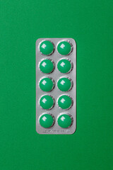 round green pills in packaging on a green background
