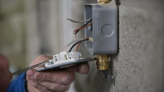 Male hands Wiring A fuse socket in garage, linking light to garage mains. metal framed socket