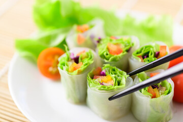 Colorful fresh vegetables salad spring roll eating with chopsticks, Healthy vegan food