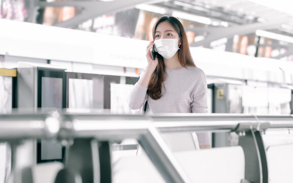 Woman wearing face mask and talking on mobile phone while standing on railway station